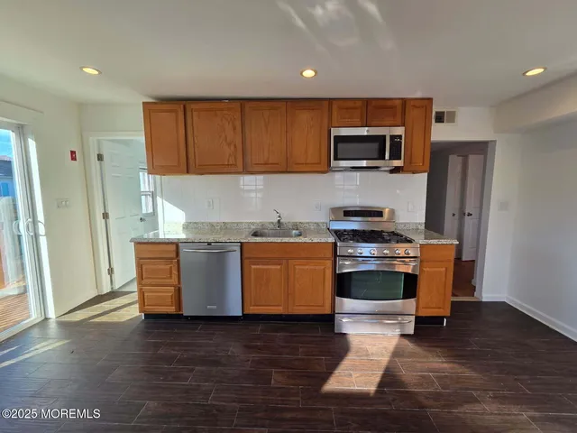 a kitchen with stainless steel appliances granite countertop a stove a sink and a refrigerator