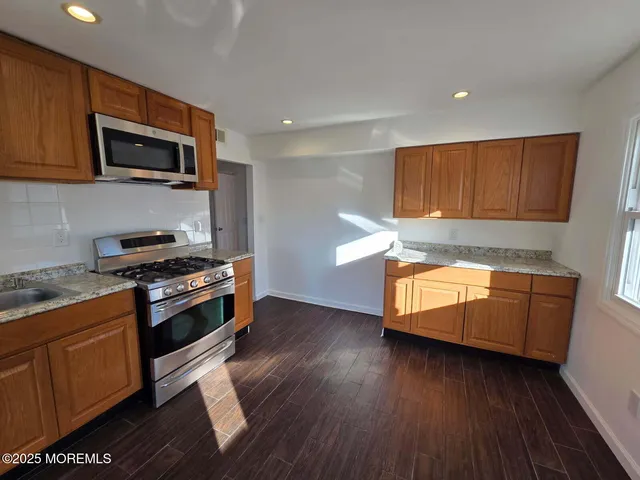 a kitchen with granite countertop wooden floors and stainless steel appliances