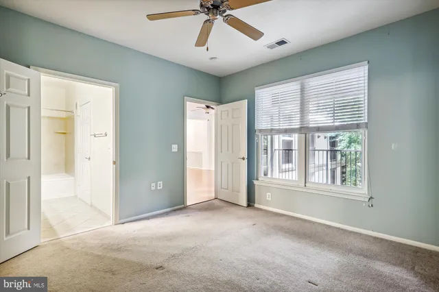 an empty room with chandelier fan and windows