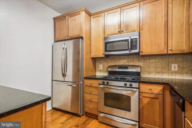 a kitchen with granite countertop wooden cabinets stainless steel appliances and a refrigerator