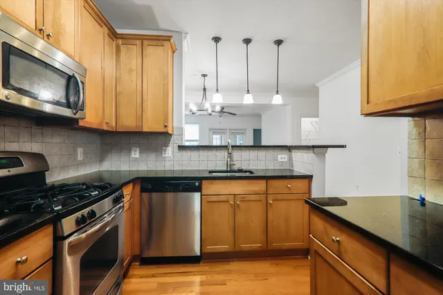 a kitchen with stainless steel appliances granite countertop a sink a stove and a microwave
