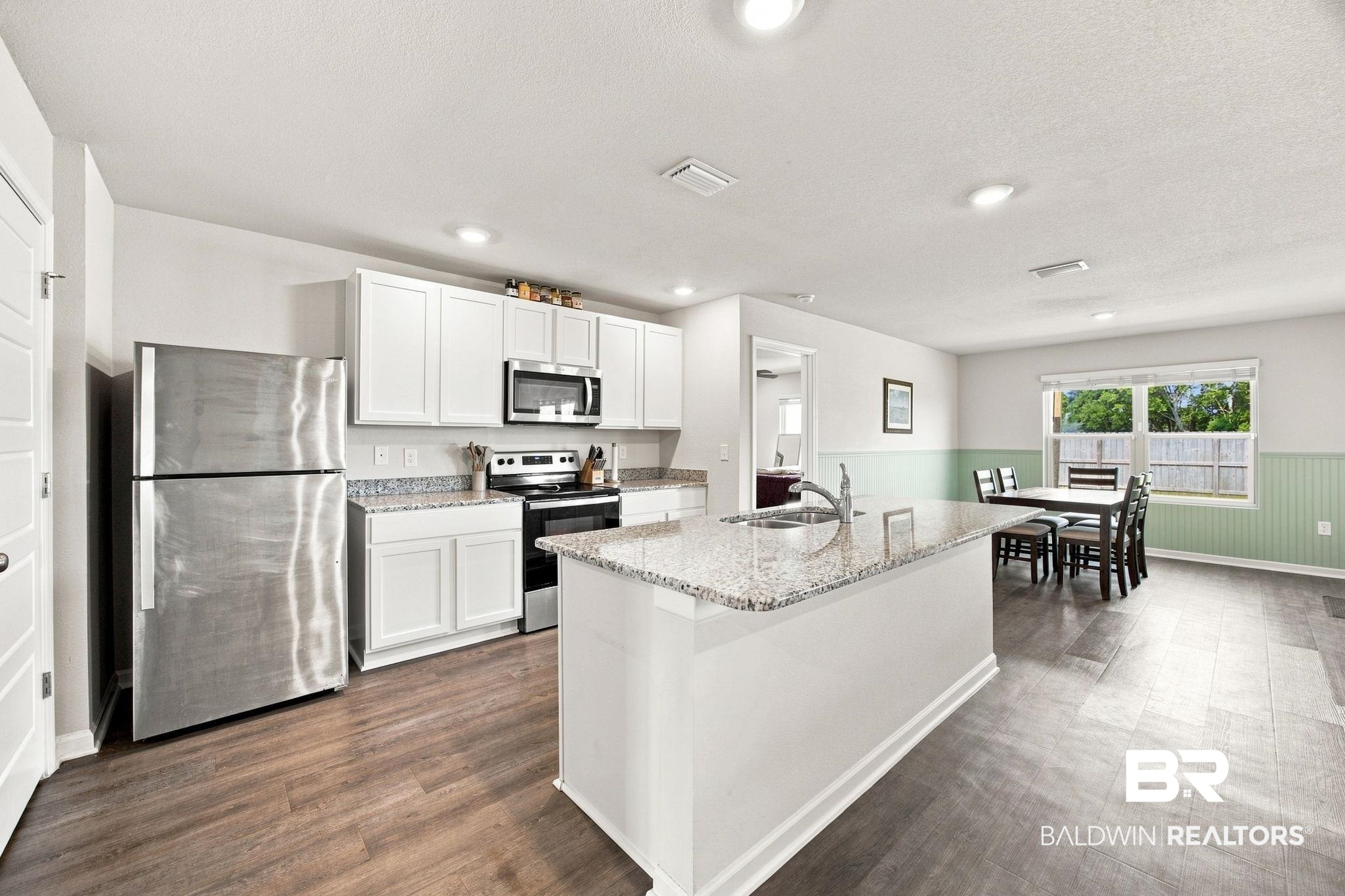 32155 Terranova Loop Lillian, AL 36549 - Photo 6 of 37 Kitchen featuring a central island with granite countertop and undermount sink, stainless steel appliances, white cabinetry, and wood-finish flooring