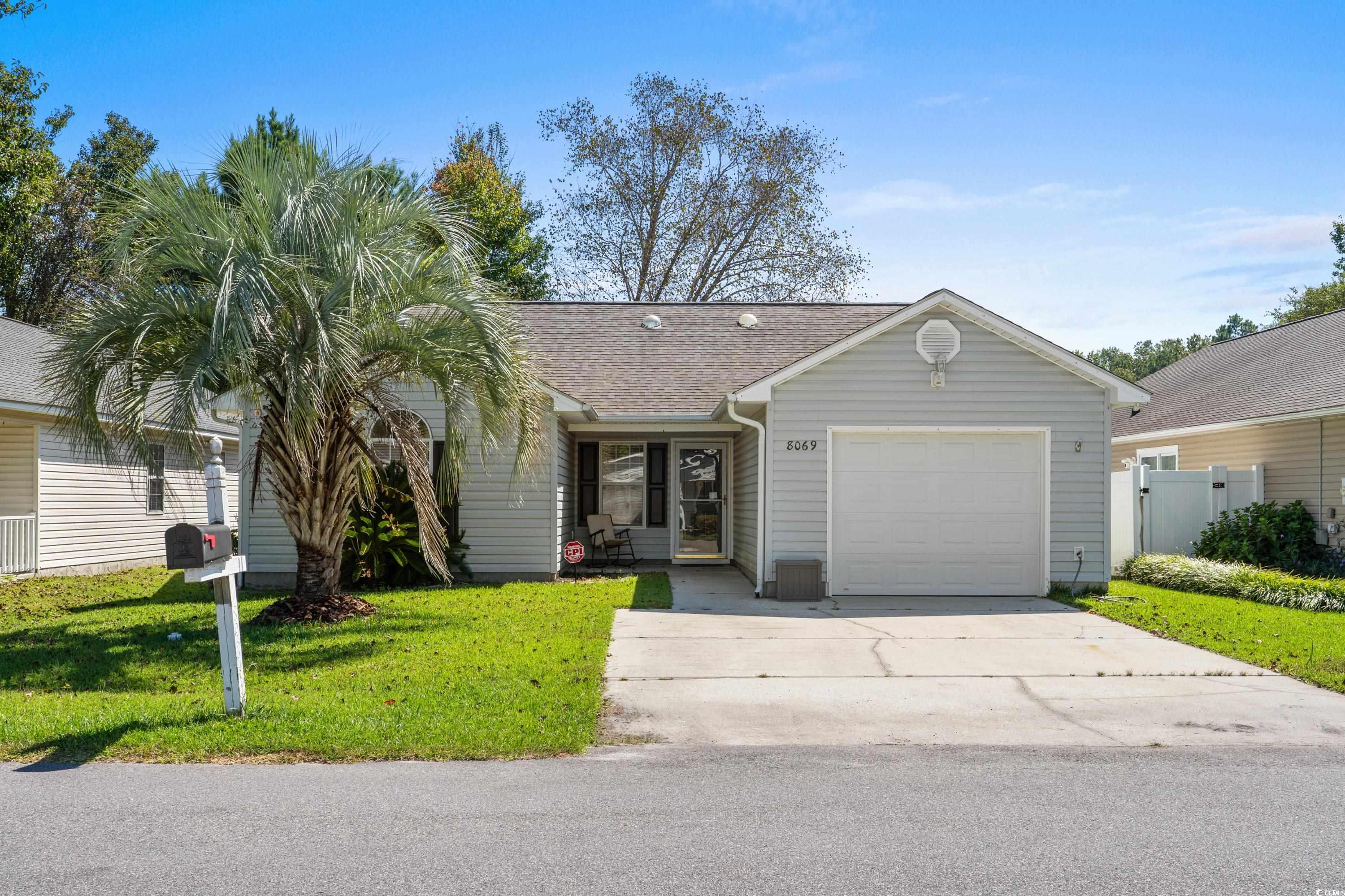 Ranch-style house featuring a shingled roof, a front yard, driveway, and a garage