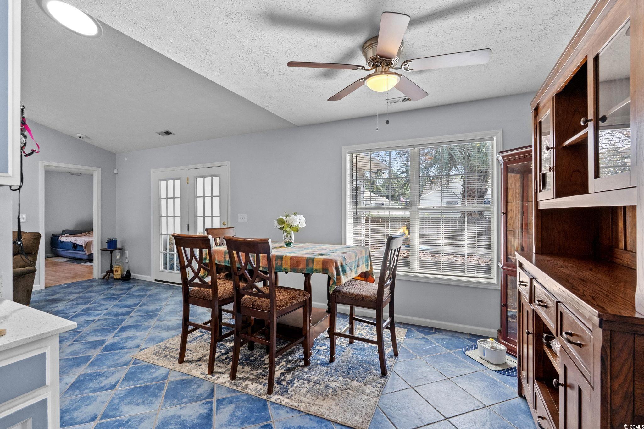 8069 Resin Road Murrells Inlet, SC 29576 - Photo 13 of 40 Dining space with a textured ceiling, french doors, ceiling fan, and dark tile patterned floors