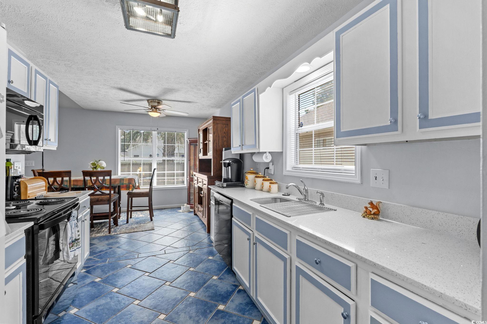 8069 Resin Road Murrells Inlet, SC 29576 - Photo 18 of 40 Kitchen featuring black appliances, healthy amount of natural light, a textured ceiling, blue cabinetry, and a ceiling fan