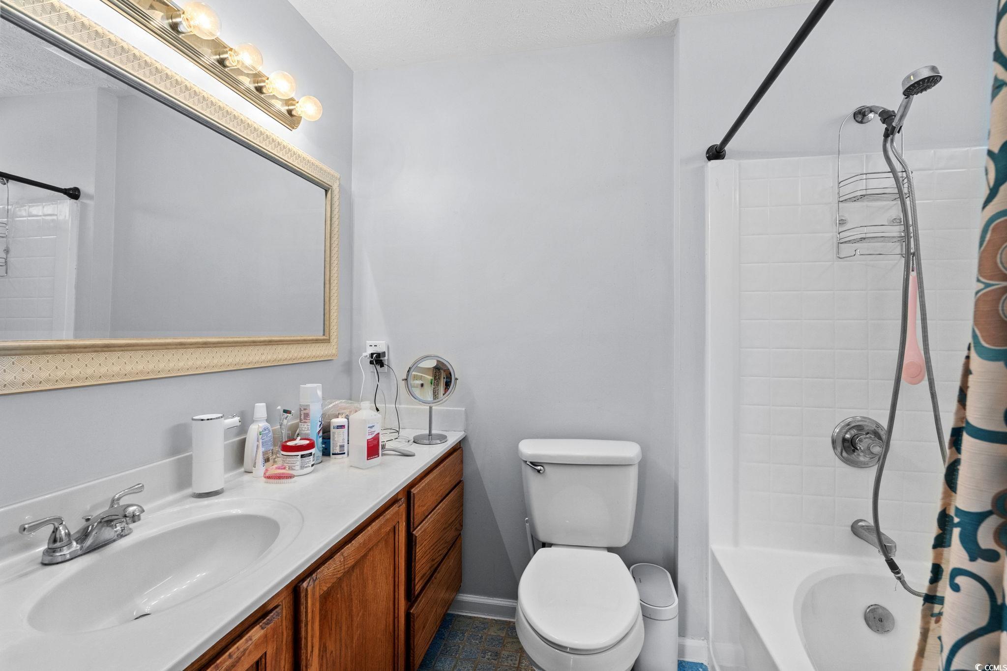 8069 Resin Road Murrells Inlet, SC 29576 - Photo 19 of 40 Full bath featuring shower / bath combo with shower curtain, vanity, and a textured ceiling