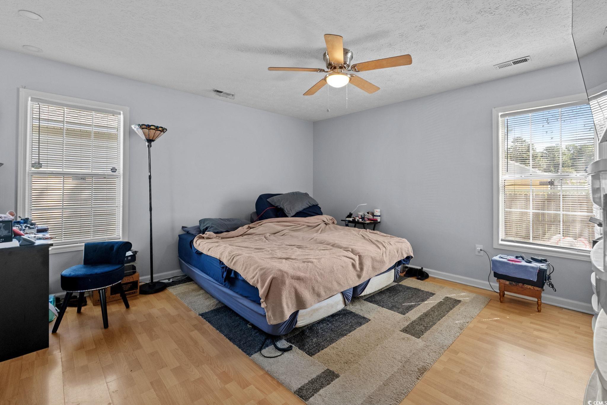 8069 Resin Road Murrells Inlet, SC 29576 - Photo 22 of 40 Bedroom with multiple windows, light wood-style floors, a textured ceiling, and a ceiling fan