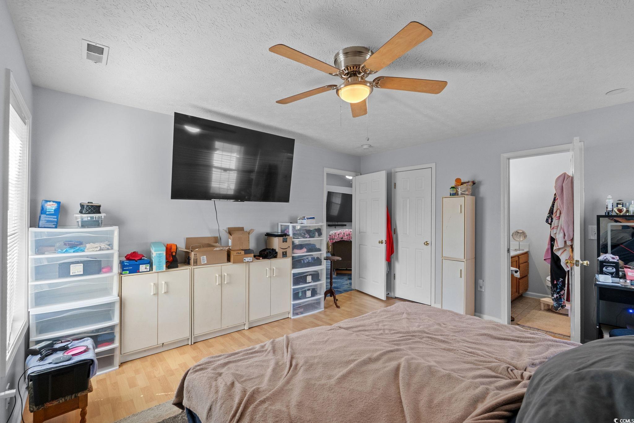 8069 Resin Road Murrells Inlet, SC 29576 - Photo 23 of 40 Bedroom with light wood-style flooring, a textured ceiling, ceiling fan, and ensuite bathroom