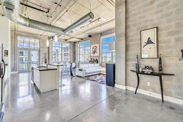 a living room with stainless steel appliances furniture a chandelier open kitchen view