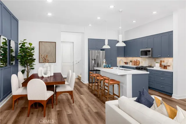 a kitchen with stainless steel appliances a table and chairs in it