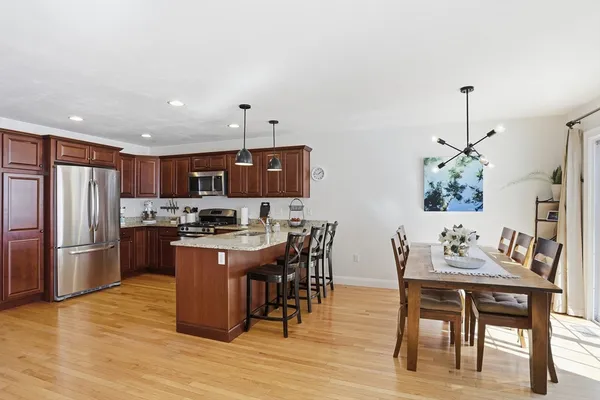 a kitchen with stainless steel appliances a dining table chairs stove and refrigerator