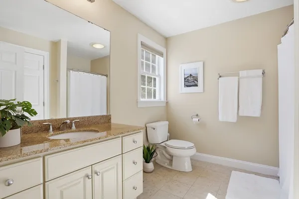 a bathroom with a granite countertop sink a toilet and a mirror