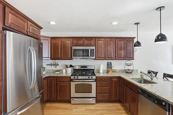 a kitchen with stainless steel appliances a stove a sink a refrigerator white cabinets and a refrigerator