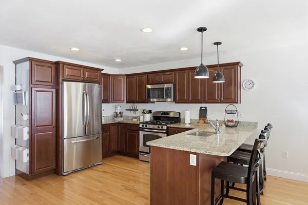 a kitchen with stainless steel appliances granite countertop a refrigerator a sink a stove a dining table and chairs