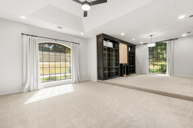 an empty room with windows and fan