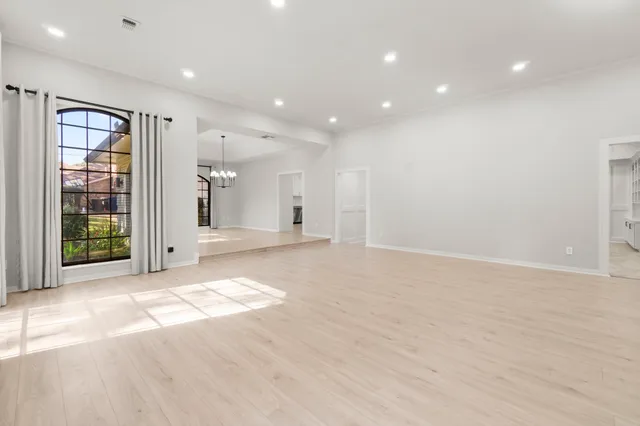 a view of an empty room with wooden floor and windows