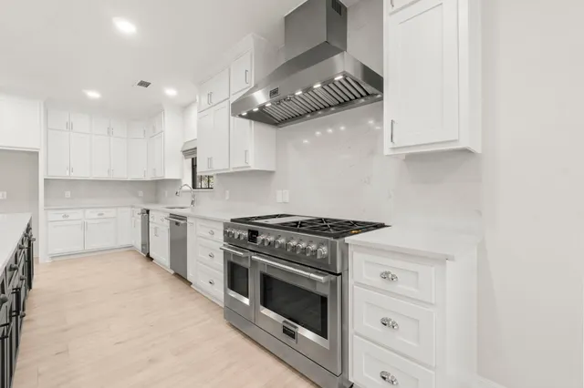 a large white kitchen with wooden floor and a large window
