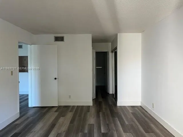 a view of an empty room with wooden floor and closet