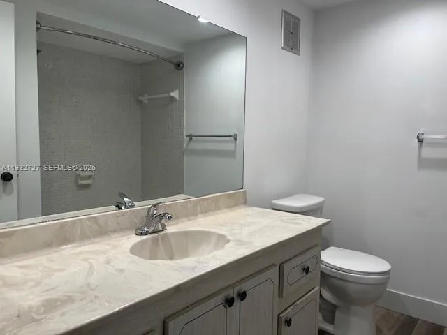 a bathroom with a granite countertop sink a toilet and a mirror