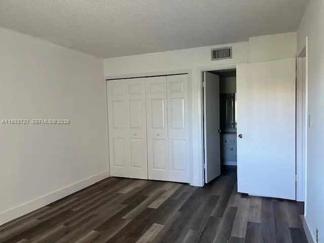 a view of an empty room with wooden floor and closet