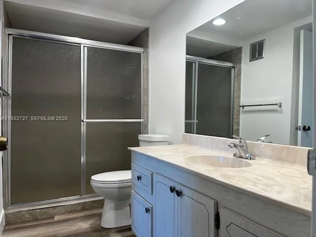 a bathroom with a granite countertop sink toilet a mirror and shower