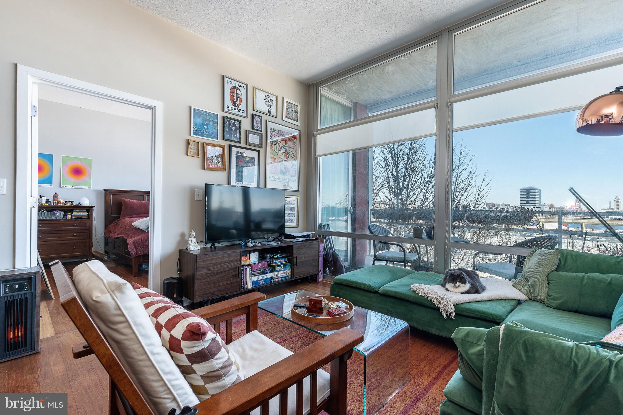22 South Front Street, Unit 207 Philadelphia, PA 19106 - Photo 8 of 32 a living room with furniture a flat screen tv and a floor to ceiling window
