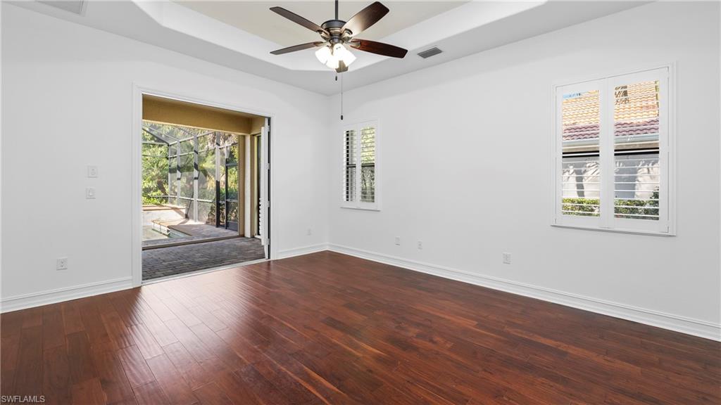 8856 Lely Island Circle Naples, FL 34113 - Photo 21 of 50 Unfurnished room featuring a raised ceiling, dark wood-style flooring, and ceiling fan