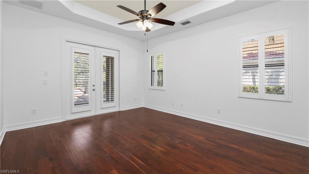 8856 Lely Island Circle Naples, FL 34113 - Photo 22 of 50 Spare room featuring a raised ceiling, dark wood-style flooring, french doors, a ceiling fan, and plenty of natural light