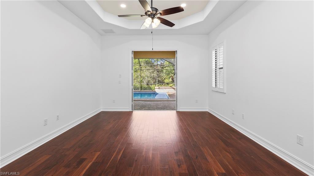 8856 Lely Island Circle Naples, FL 34113 - Photo 22 of 50 Spare room featuring ceiling fan, a raised ceiling, dark wood-style floors, a sunroom, and recessed lighting