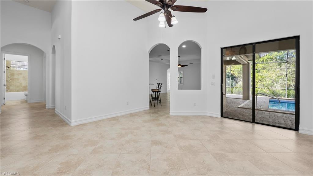 8856 Lely Island Circle Naples, FL 34113 - Photo 10 of 50 Spare room featuring arched walkways, ceiling fan, a high ceiling, and light tile patterned floors