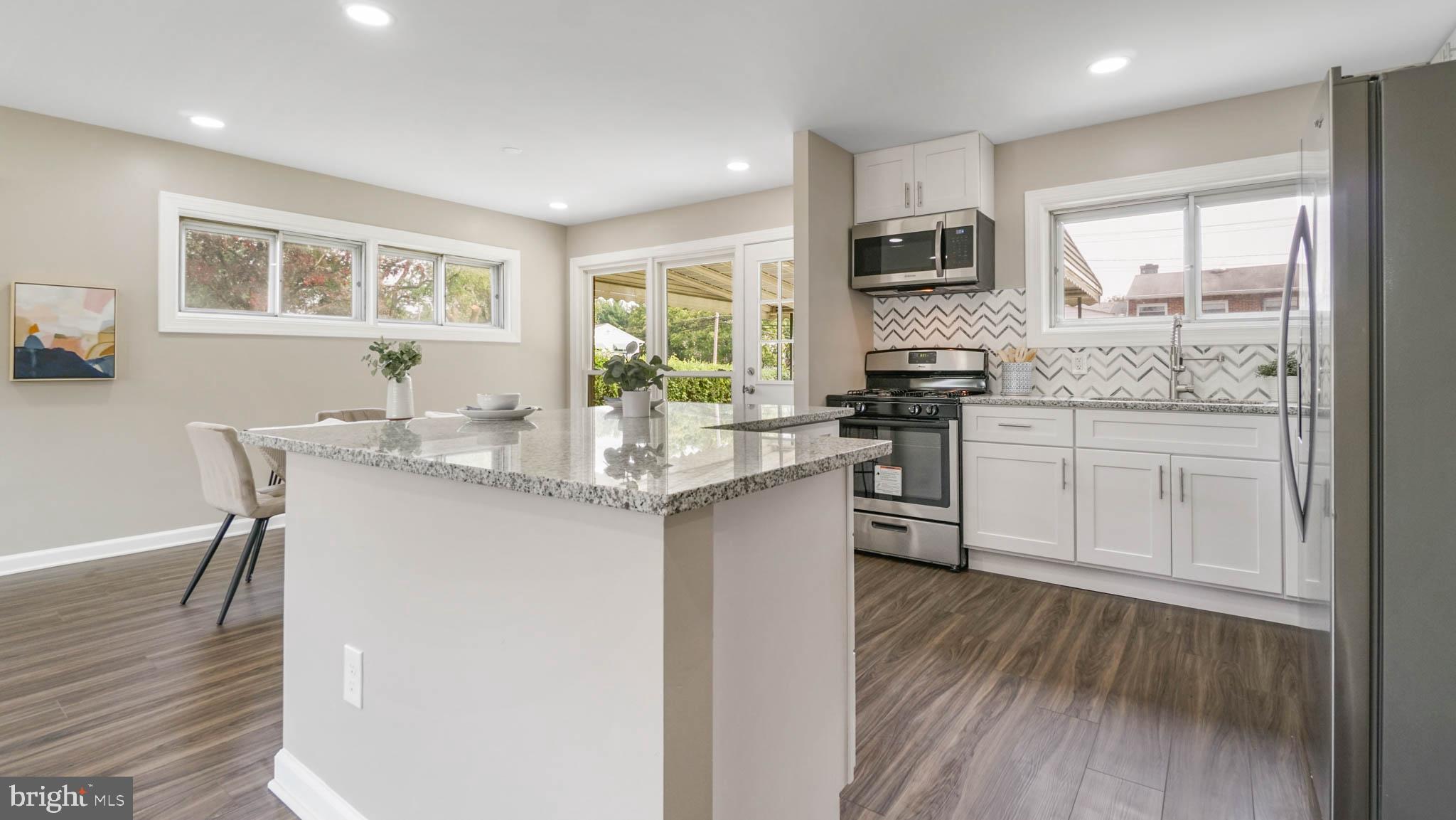 5932 Charnwood Road Baltimore, MD 21228 - Photo 4 of 21 a kitchen with stainless steel appliances granite countertop a stove top oven a sink dishwasher a dining table and chairs with wooden floor