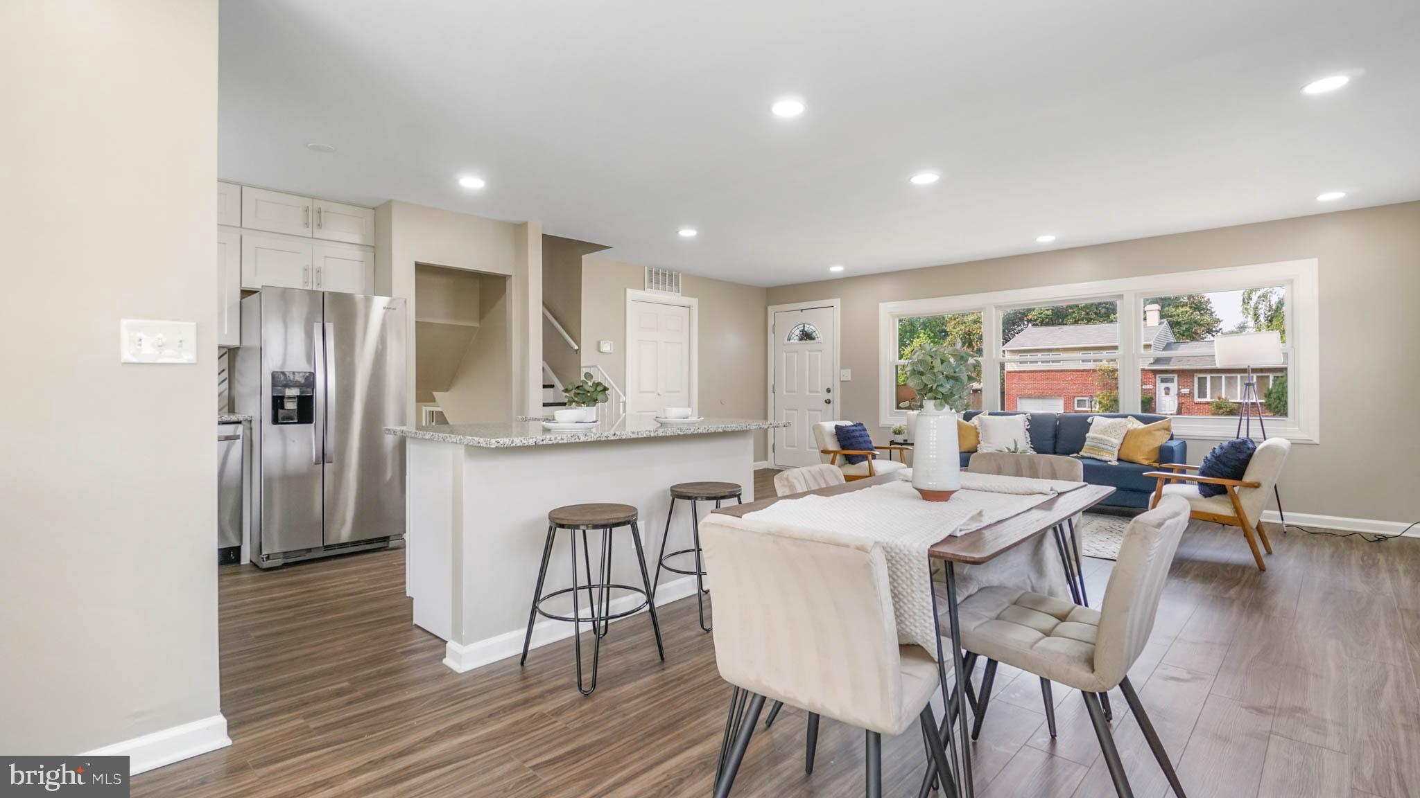 5932 Charnwood Road Baltimore, MD 21228 - Photo 21 of 21 a kitchen with stainless steel appliances granite countertop a dining table chairs refrigerator sink and cabinets