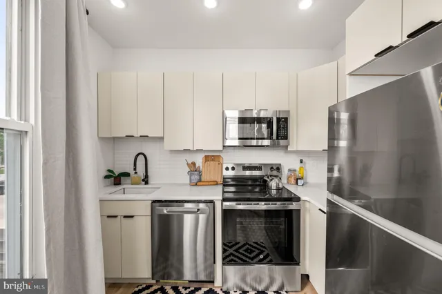 a kitchen with stainless steel appliances a stove a sink a refrigerator and cabinets