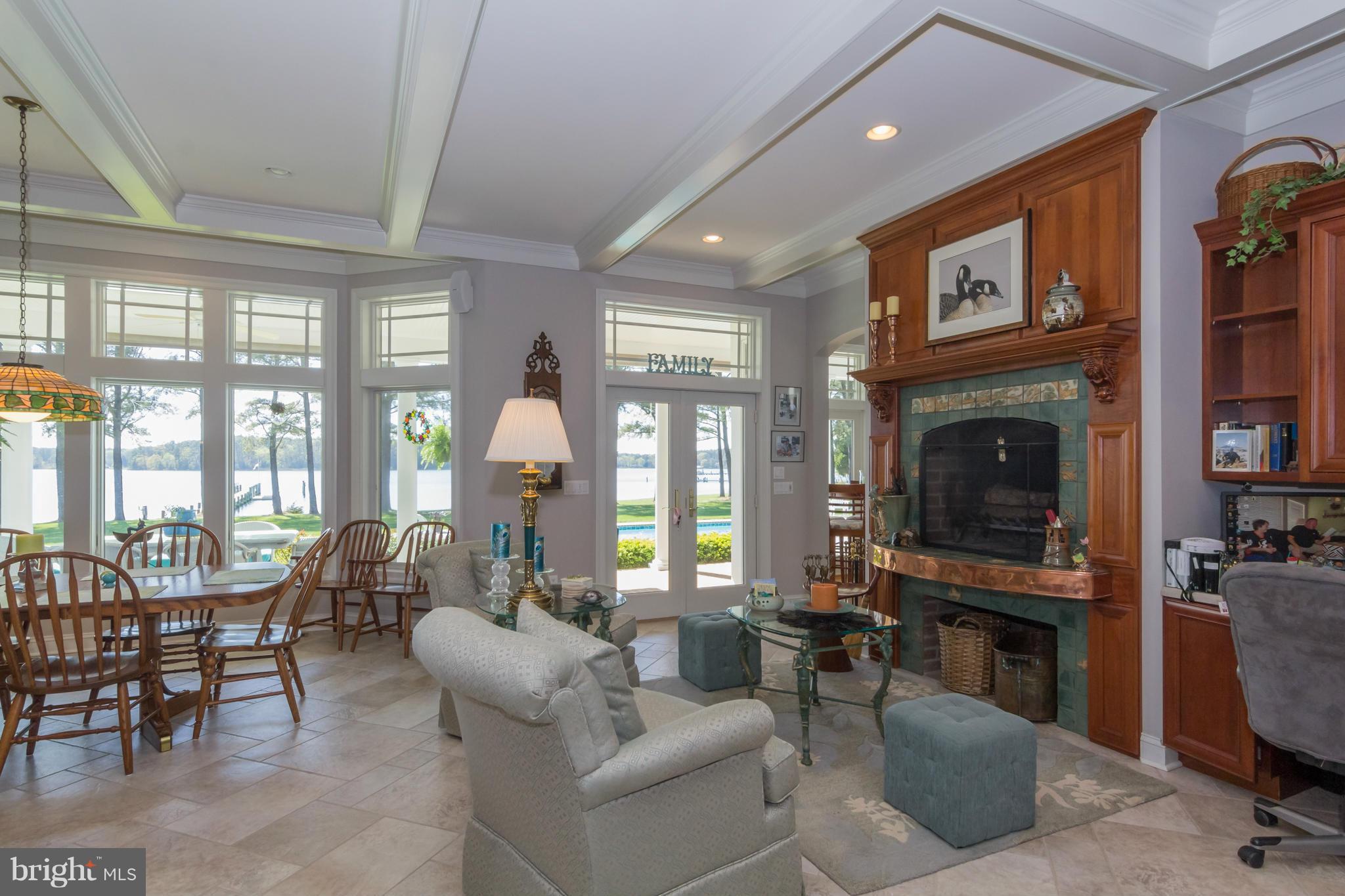 8092 Church Neck Road St. Michaels, MD 21663 - Photo 12 of 27 a living room with furniture a fireplace and a floor to ceiling window