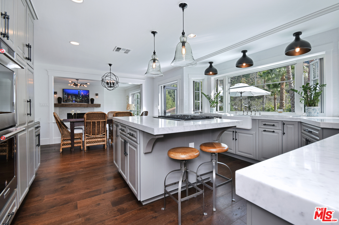 560 Cold Canyon Road Calabasas, CA 91302 - Photo 17 of 38 a kitchen with stainless steel appliances granite countertop a stove a sink dishwasher a dining table and chairs with wooden floor