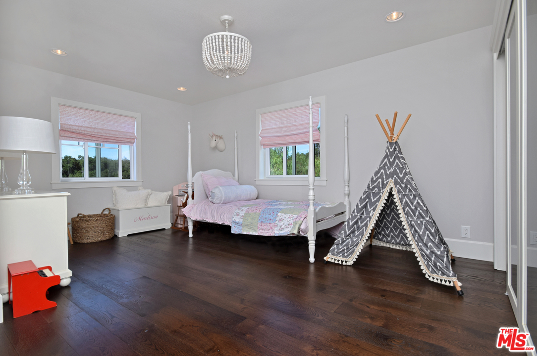 560 Cold Canyon Road Calabasas, CA 91302 - Photo 28 of 38 a room with furniture wooden floor and a chandelier