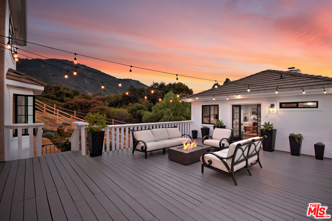 560 Cold Canyon Road Calabasas, CA 91302 - Photo 37 of 38 a view of a patio with couches and table and chairs with wooden floor