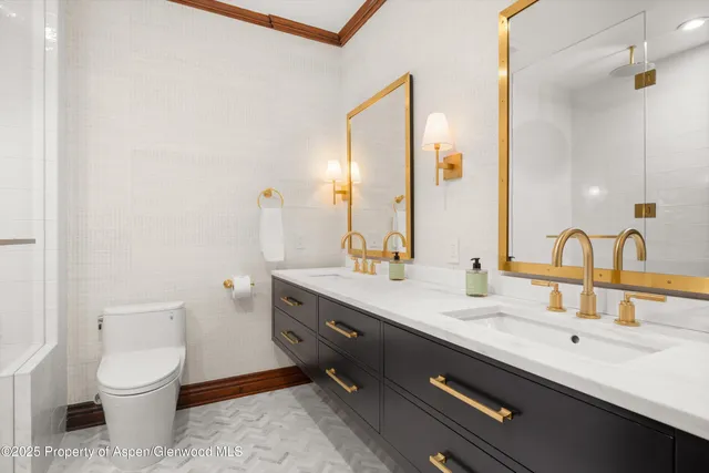 a bathroom with a toilet sink double vanity and mirror