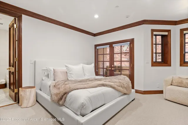 a large white bed sitting in a bedroom next to a window