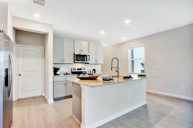 a kitchen with stainless steel appliances granite countertop a stove a sink a refrigerator a microwave and cabinets