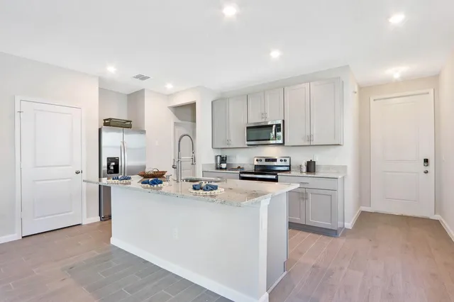 a kitchen with stainless steel appliances a stove a sink a refrigerator a microwave and cabinets