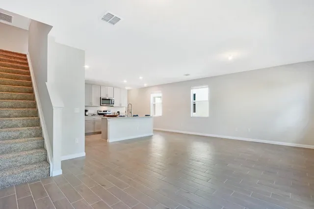 a view of a living room a kitchen with wooden floor and stairs