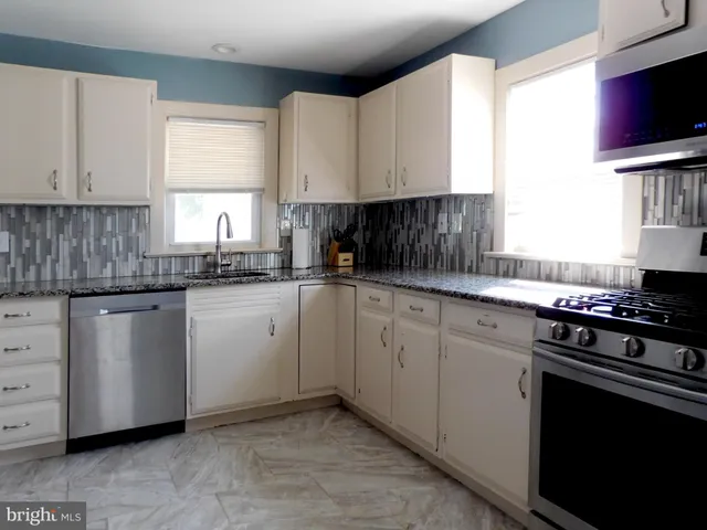 a kitchen with cabinets appliances a sink and a window