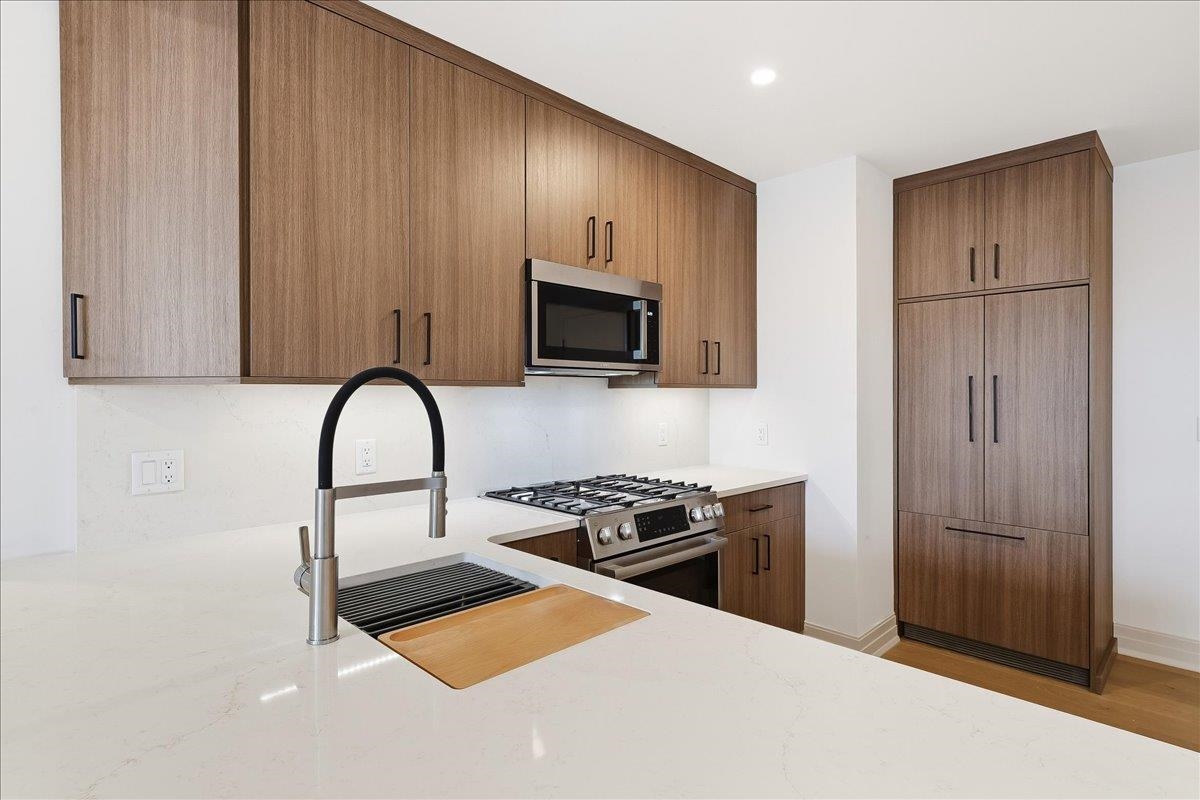 921 Madison Street, Unit 604 Hoboken, NJ 07030 - Photo 2 of 22 a kitchen with stainless steel appliances a refrigerator stove and microwave