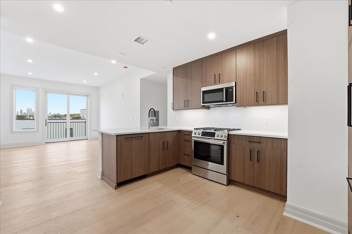 921 Madison Street, Unit 604 Hoboken, NJ 07030 - Photo 6 of 22 a kitchen with stainless steel appliances kitchen island granite countertop a stove a sink and a refrigerator
