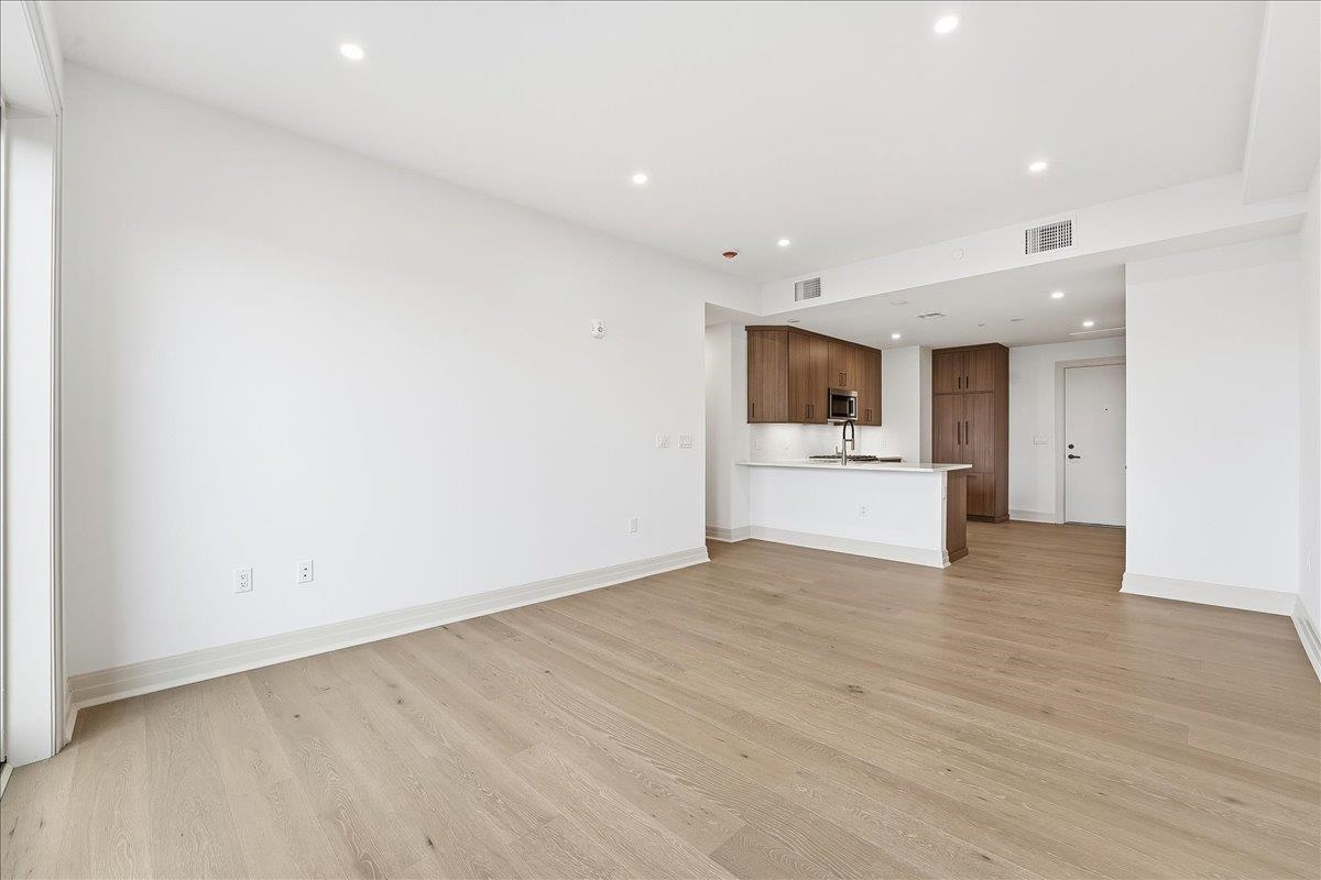 921 Madison Street, Unit 604 Hoboken, NJ 07030 - Photo 8 of 22 a view of an empty room with wooden floor and a kitchen