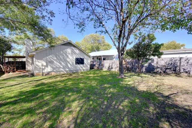 a backyard of a house with lots of plants and large tree