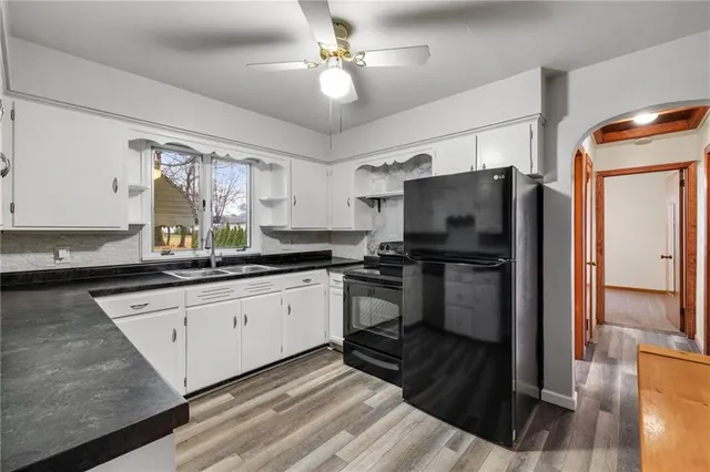 a kitchen with granite countertop a refrigerator a sink a stove and white cabinets
