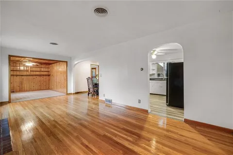 a view of empty room with wooden floor and fan