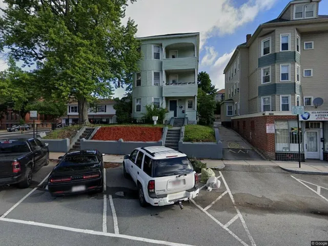 a front view of a building with cars parked